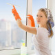 Junge Frau beim Fenster putzen